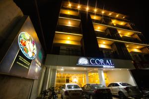 a building with cars parked in front of a restaurant at CORAL RESIDENCY in Rāmanāthapuram