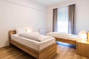 dwa łóżka w pokoju z oknem w obiekcie Appartement Graz - Ihr erstklassiges Zuhause fernab von Zuhause w Grazu