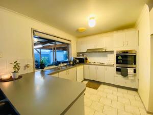 a large kitchen with white cabinets and a large window at ENTIRE HOME IN WERRIBEE,BEST POSSIBLE LOCATION YOU CAN FIND in Werribee