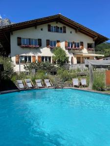 a swimming pool with chairs and a house in the background at Villa Monkey in Brienz