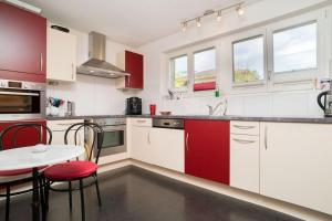 une cuisine avec des placards rouges et blancs et une table dans l'établissement Villa Monkey, à Brienz