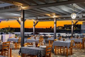 a restaurant with tables and chairs with the sunset in the background at Chrysomare Beach Hotel & Resort in Ayia Napa