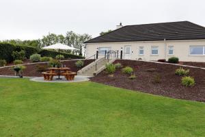 un jardín con una mesa de picnic y una casa en Laneside Haven - 5 Minutes from Castleblayney - Accessible, Gated with Patio, Garden and Gym! en Monaghan