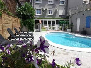 a swimming pool with two chairs next to a building at Hotel Le Majestic Canet plage in Canet-en-Roussillon