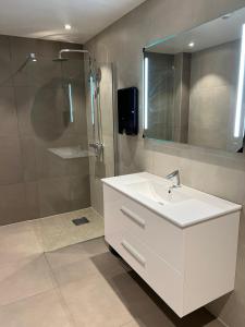 La salle de bains est pourvue d'un lavabo blanc et d'une douche. dans l'établissement Aktivitetsbyen Gamle Fredrikstad, à Fredrikstad