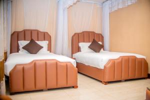 two beds in a room with two large orange beds at Hera Hotel Kampala in Kampala