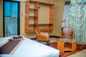 a room with a bed and two chairs and a toilet at Hera Hotel Kampala in Kampala
