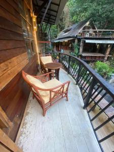 a deck with two chairs and a table on it at ไชยพล โฮมสเตย์ หมู่บ้านแม่กำปอง in Ban Pok Nai