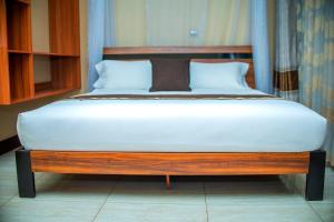 a bed in a room with a wooden bed frame at Hera Hotel Kampala in Kampala