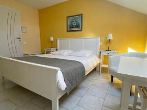 a bedroom with a large white bed and a table at Chambre d'hôtes LA COLOMBE in Xouaxange