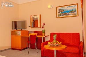 a living room with a couch and a table with a television at Hotel Marina in Selce