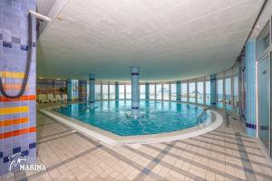a large swimming pool in a building with windows at Hotel Marina in Selce