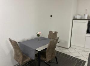 una mesa con sillas y un jarrón de flores. en A.M.C. Ferienwohnung en Karlstadt