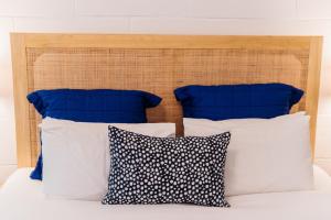 a bed with blue and white pillows and a wooden headboard at Port O' Call Motel in Port Campbell