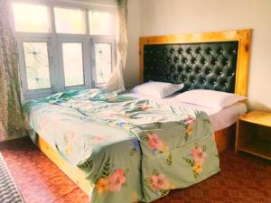 una camera da letto con un letto con copriletto floreale e una finestra di Cupidtrails Himalayan Castle a Manāli