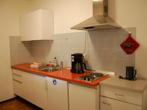 een keuken met witte kasten en een rood aanrecht bij Gasthaus Rehwinkel in Titisee-Neustadt
