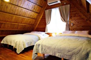 two beds in a wooden room with a window at にらい恩納　杉の木 in Onna +77 photos