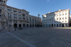 duży dziedziniec z dwoma dużymi białymi budynkami w obiekcie Grand Hotel Duchi d'Aosta Apartments w Trieście