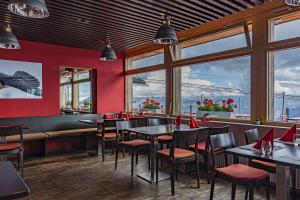 a restaurant with tables and chairs and windows at Berghaus Niederhorn in Beatenberg