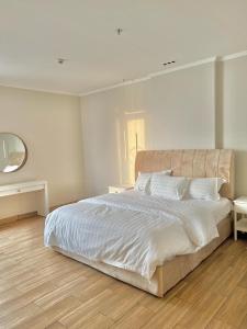 1 dormitorio con 1 cama blanca grande y espejo en شقة فاخرة vip مطلة على البحر برج المسارات, en Yeda