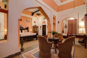 een woonkamer met een bed en een tafel en stoelen bij The Dadhikar Fort Alwar in Alwar