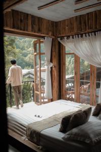 a man standing in a bedroom looking out the window at ไชยพล โฮมสเตย์ หมู่บ้านแม่กำปอง in Ban Pok Nai