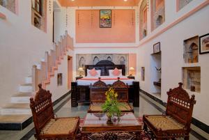 um quarto com uma cama, uma mesa e cadeiras em The Dadhikar Fort Alwar em Alwar