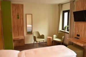 um quarto de hotel com uma cama e duas cadeiras e uma televisão em Der Höfener Garten em Nurembergue