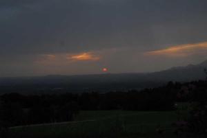 een zonsondergang boven een veld met de zon in de verte bij Hof Rossruck in Fischbachau