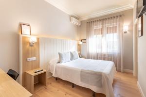 een slaapkamer met een wit bed en een raam bij Hotel Artaza in Getxo