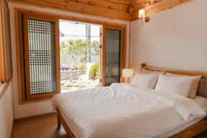1 dormitorio con cama blanca y ventana en Gyeongju Hanok Sohwa en Gyeongju