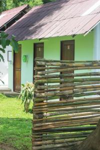 a wooden fence in front of a green house at Pai Flora Resort in Pai