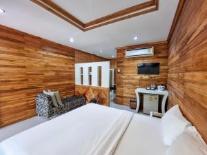a bedroom with wooden walls and a bed and a tv at Phuvara Boutique Aonang in Ao Nang Beach