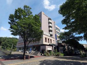 um edifício alto com uma árvore em frente em Chisun Inn Yokohama Tsuzuki em Yokohama