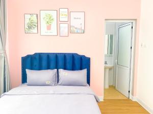 a bedroom with a blue headboard and a pink wall at Luxury Villa Ha Long in Ha Long