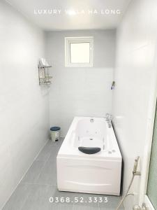 a white bathroom with a bath tub in the corner at Luxury Villa Ha Long in Ha Long