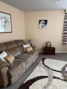 a living room with a brown couch and a rug at The Old Pie Shop Hebden Bridge in Hebden Bridge