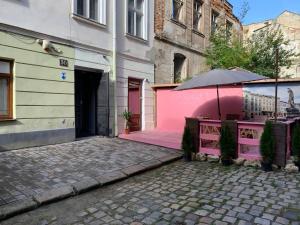 um edifício cor-de-rosa com um guarda-chuva numa rua em Ivana Fedorova 30 em Lviv