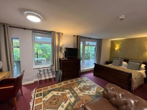 1 dormitorio con cama, sofá y TV en The Chainbridge Hotel en Llangollen