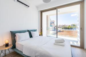 sypialnia z dużym białym łóżkiem i dużym oknem w obiekcie Cyan 3-Bedroom Villa in Protaras w mieście Paralimni