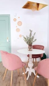 a table with two pink chairs and a vase with flowers at Meraki: tu hogar en Frigiliana in Frigiliana