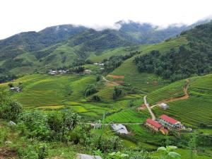a village in the middle of a green hillside at Má Si H'MÔNG HOMESTAY Tả Phìn in Sapa
