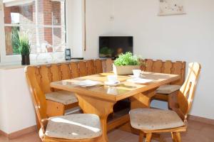 a wooden dining room table with chairs and a television at Dat-Steenhuus in Marienhafe