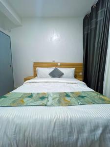 een slaapkamer met een groot bed met een deken erop bij Rebero View Apartments in Kigali