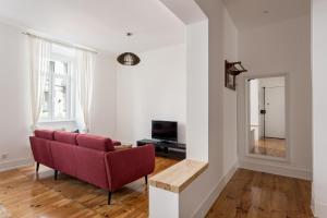 uma sala de estar com um sofá vermelho e uma mesa em JOIVY Spacious Arroios Flat, Easy Access to the Centre em Lisboa