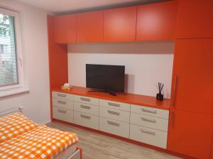 a living room with a tv and orange cabinets at Penzion Školička in Prague