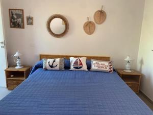 una camera da letto con letto blu, cuscini e specchio di Flaviana Salento Holiday House a Pulsano