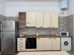 una cucina con armadietti bianchi e frigorifero di Flaviana Salento Holiday House a Pulsano