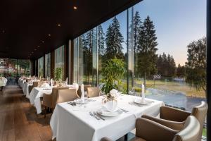 a restaurant with white tables and chairs and large windows at Ana Hotels Sport Poiana Brasov in Poiana Brasov