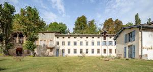 ein großes weißes Gebäude mit einem Hof in der Unterkunft Ancienne fabrique de soie À la Galicière in Chatte